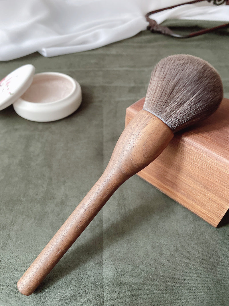 Makeup brush with wooden handle and natural bristles.