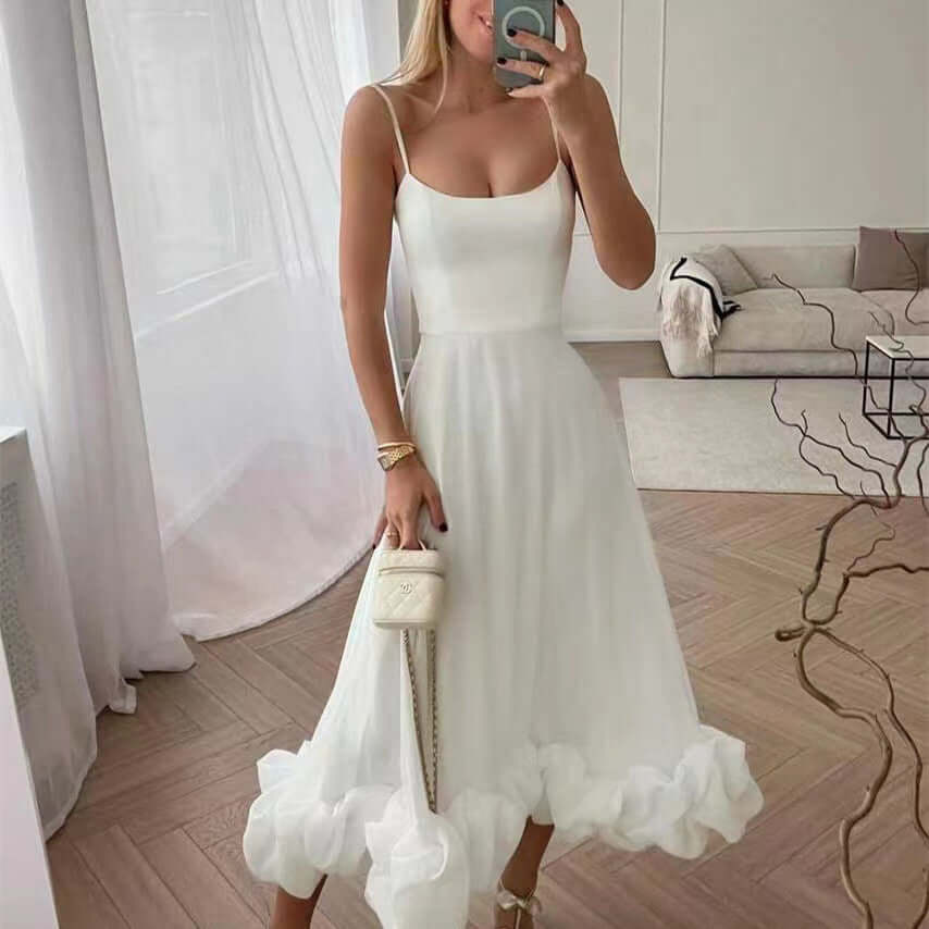 Woman wearing a white A-line dress with ruffled hem, showcasing a stylish and elegant look in a bright interior.