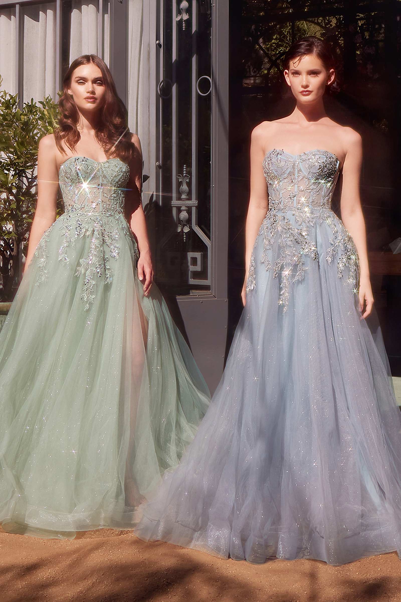 Two women wearing strapless evening gowns in green and blue.