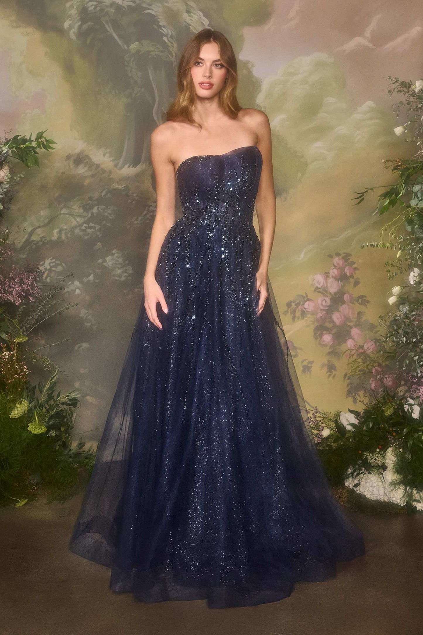 Woman wearing a dark blue strapless gown against a floral backdrop