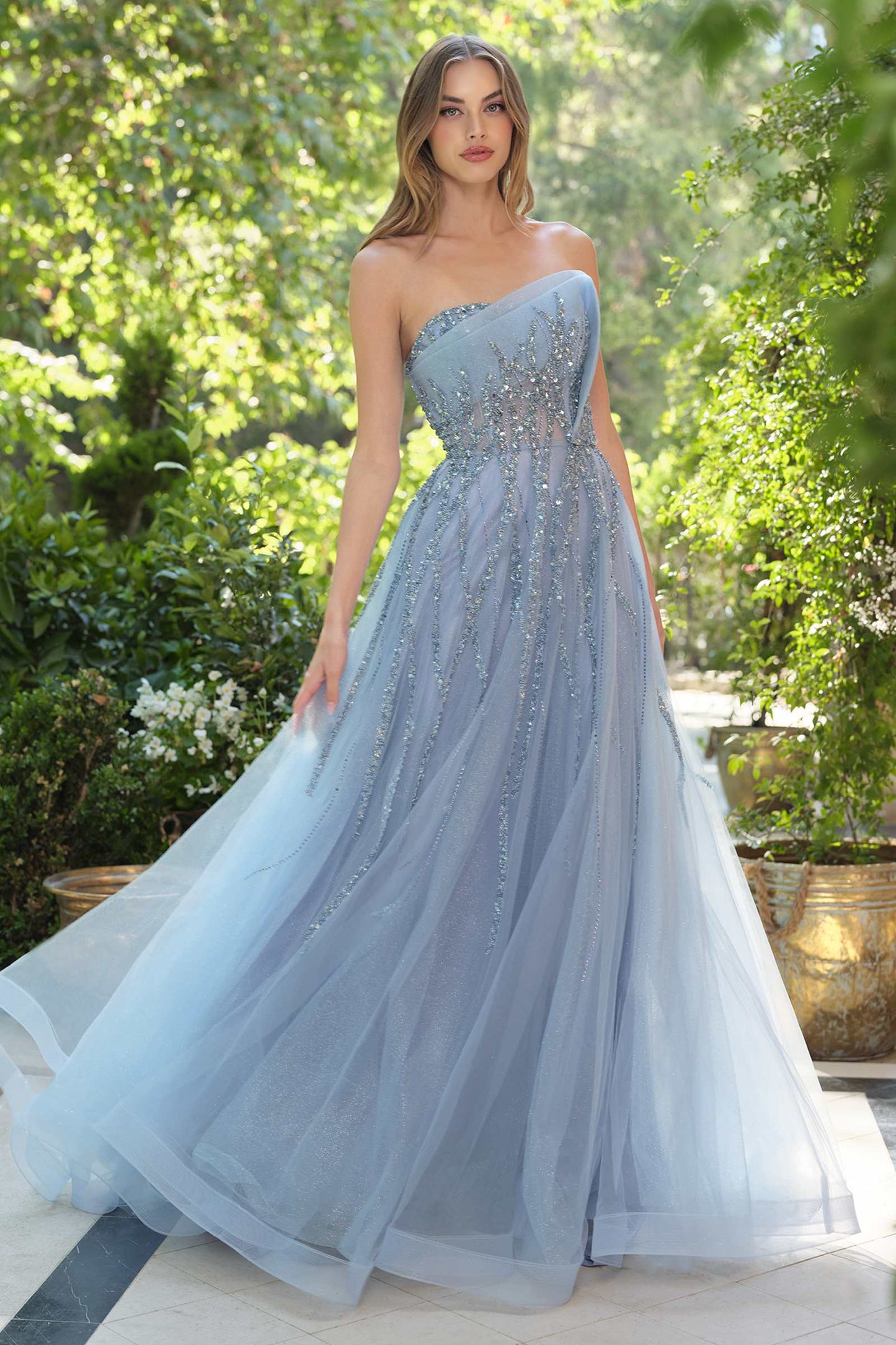 Woman wearing a light blue strapless gown with beaded details in an outdoor setting.