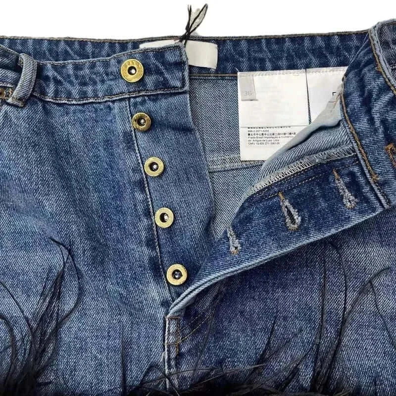 Close-up of trendy women's denim skirt with gold buttons and feather edge detailing, perfect for casual outings.