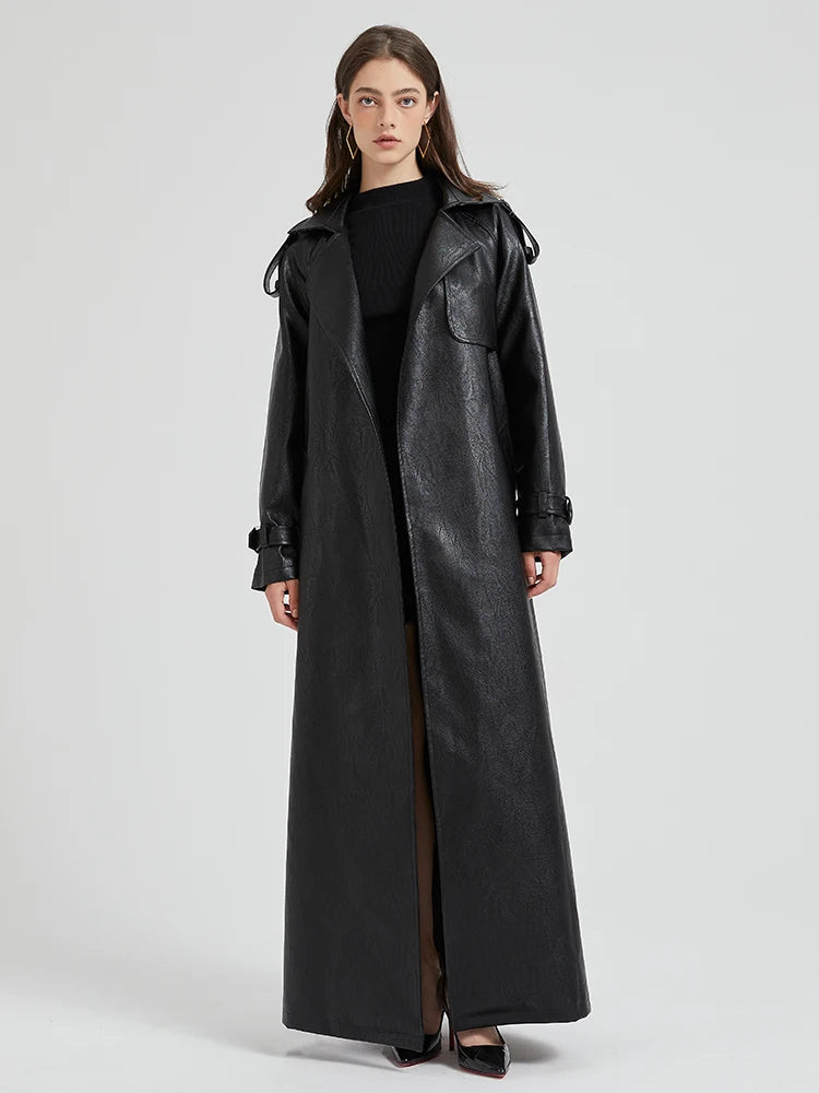 A woman wearing a long black leather coat.