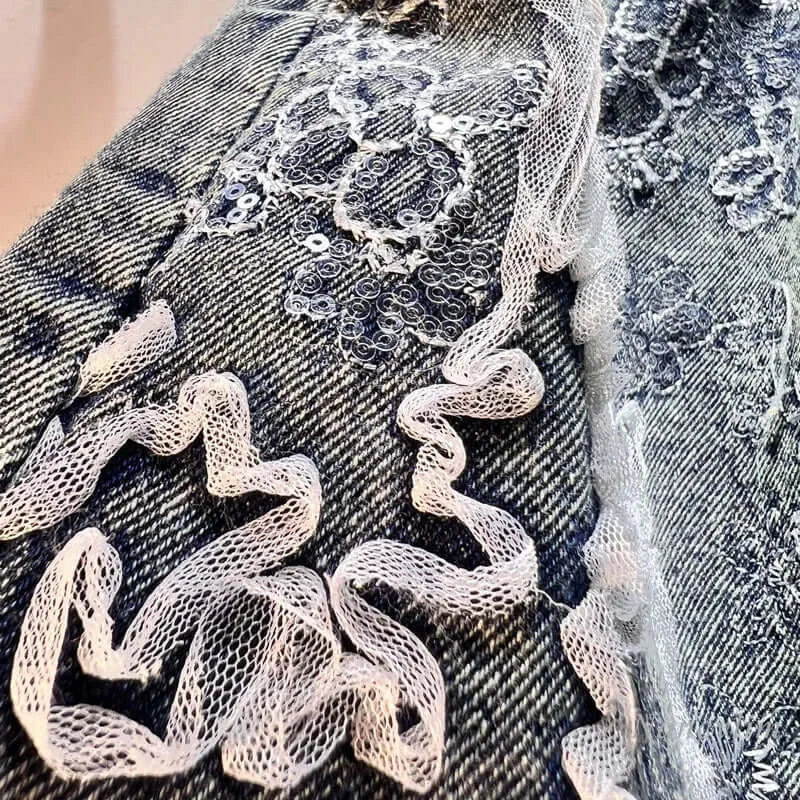 Close-up of splicing mesh embroidery and sequins on denim fabric for wide leg shorts.