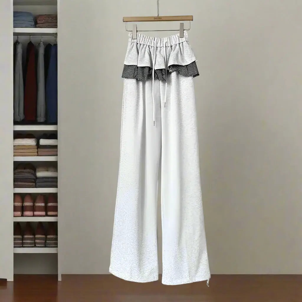 Women's white patchwork plaid pants with ruffled waistband showcasing a stylish and comfortable design against a wardrobe backdrop.