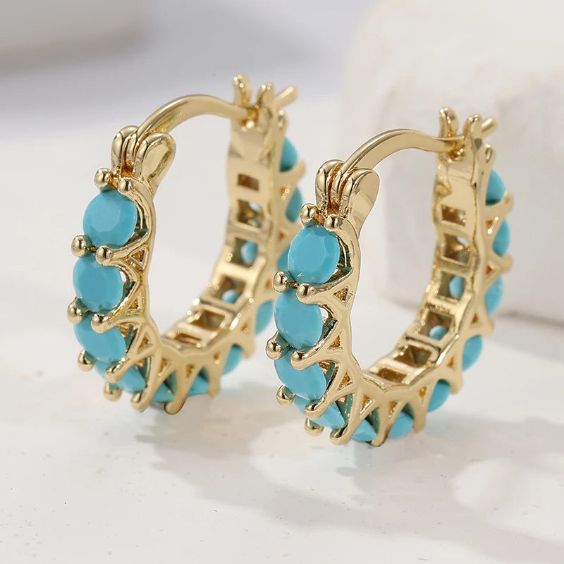 Gold hoop earrings with turquoise stones.