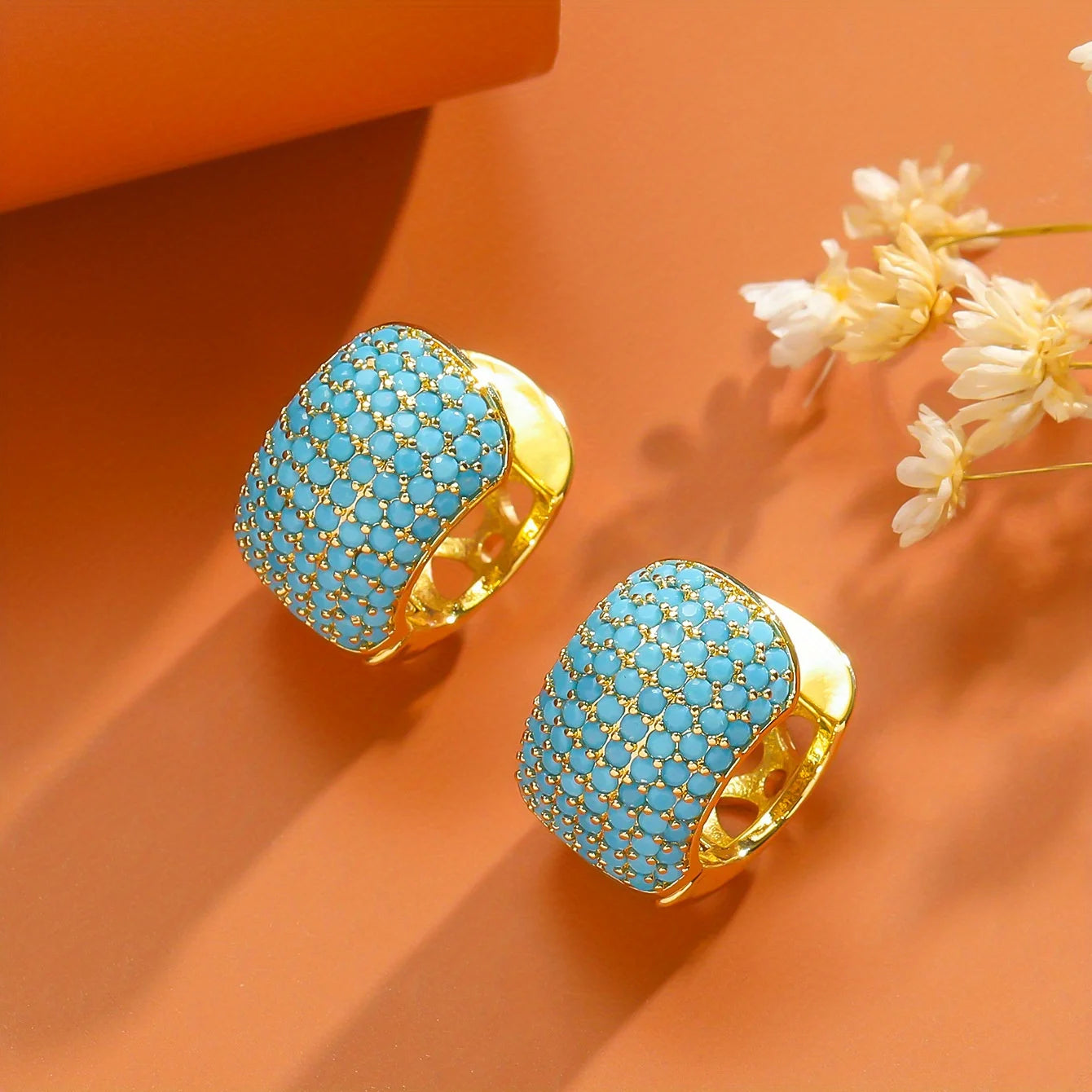 Turquoise earrings with gold accents on.