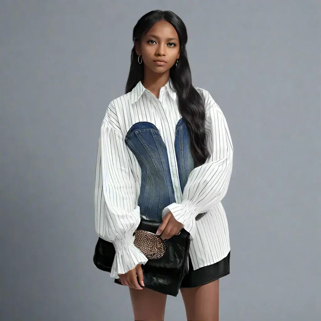 Fashionable woman wearing a trendy long sleeves single breasted blouse with denim accents, holding a stylish clutch.