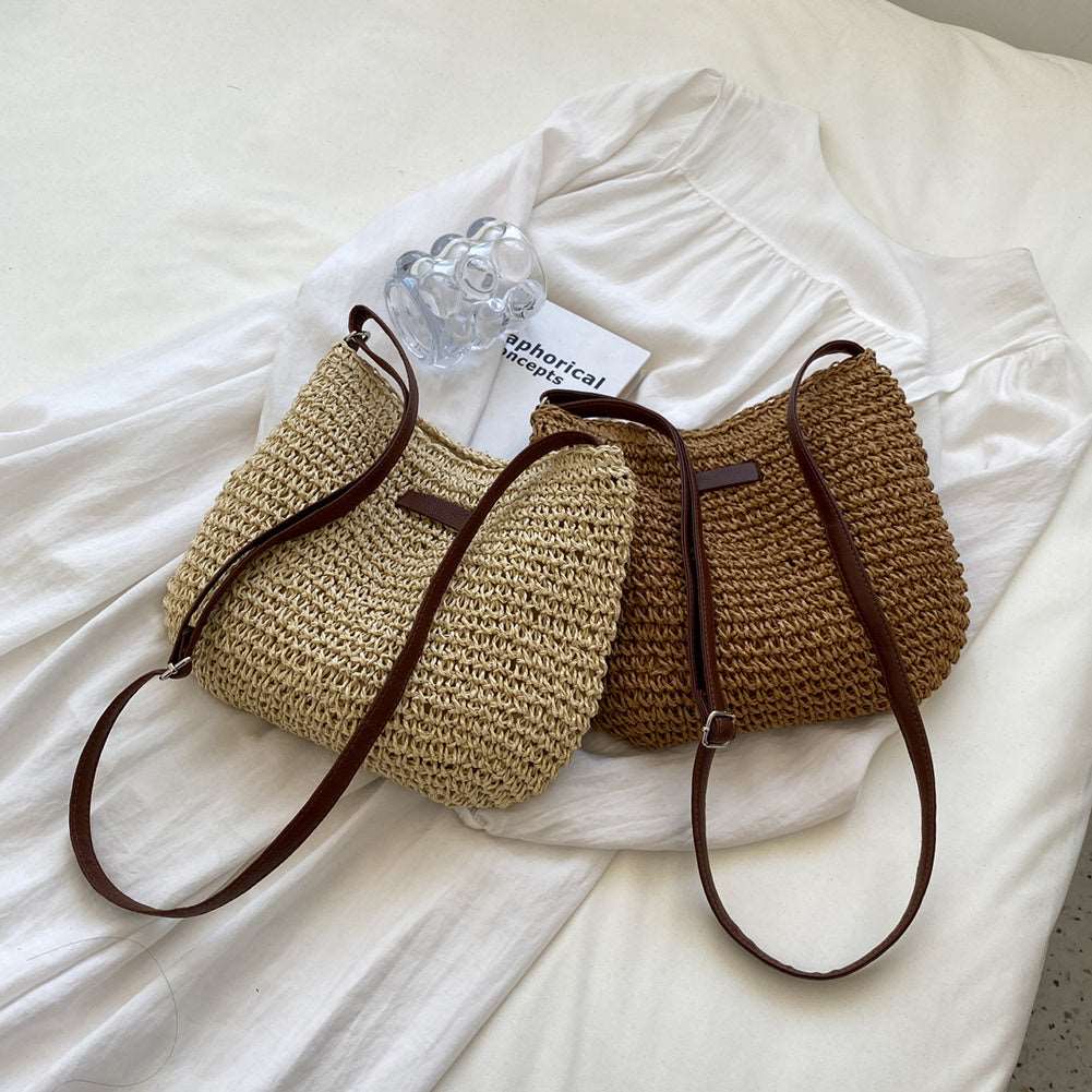 A beige and brown Vacation Straw Tote Bag from HalleBeauty, featuring straw material with leather straps, are artfully placed on a white shirt alongside a clear hair clip and small white card. Perfect for beach trips, this setup embodies casual elegance.