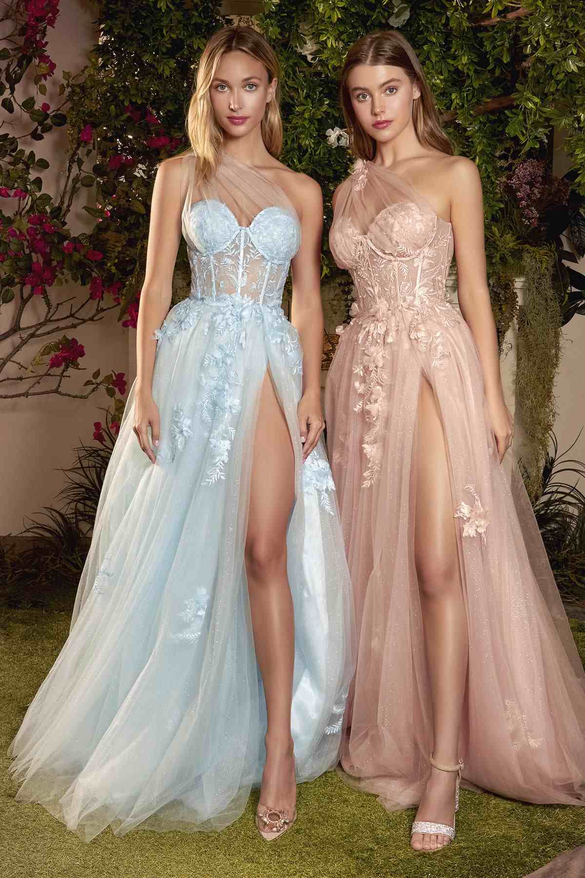 Two women in elegant evening gowns standing outdoors with floral decorations.