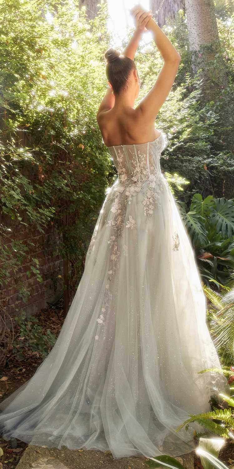 Woman in a strapless, embellished wedding dress standing in a forest setting.