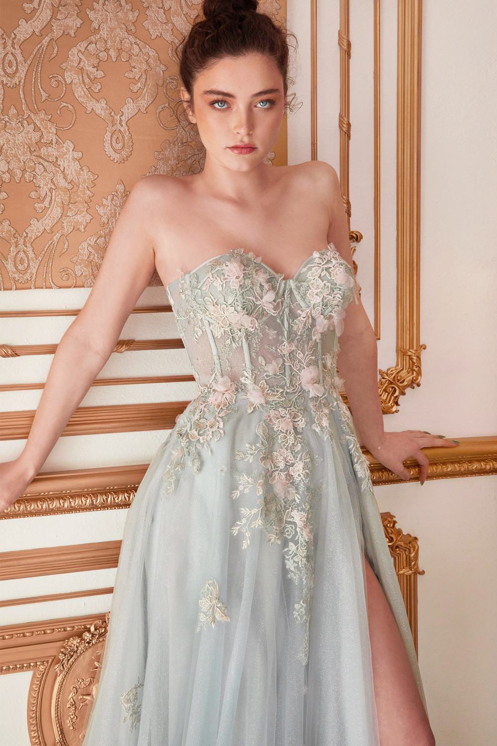 Woman in a light blue floral dress standing in an ornate room.